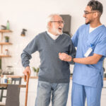 a care giver explaining NDIS Benefits from Regular Physiotherapy to an elderly man at a Home
