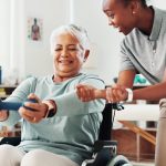 Physiotherapist helping older women with exercises in wheelchair