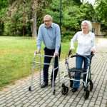 Senior citizens walking through the park with walking aid