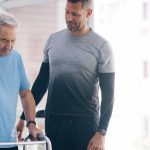 Physiotherapist assisting a man with rollator to walk