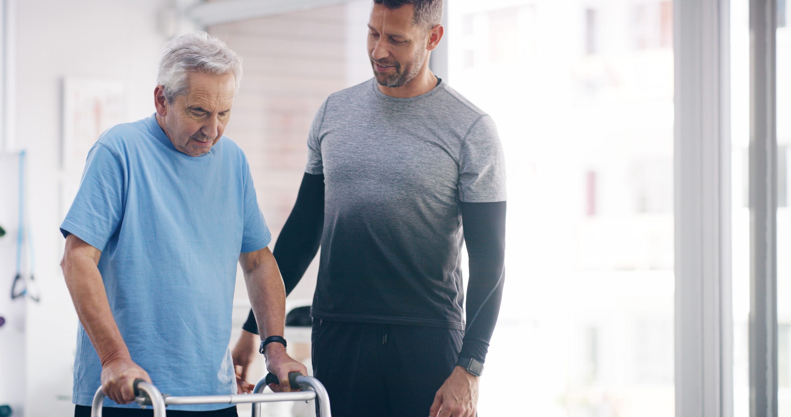 Physiotherapist assisting a man with rollator to walk