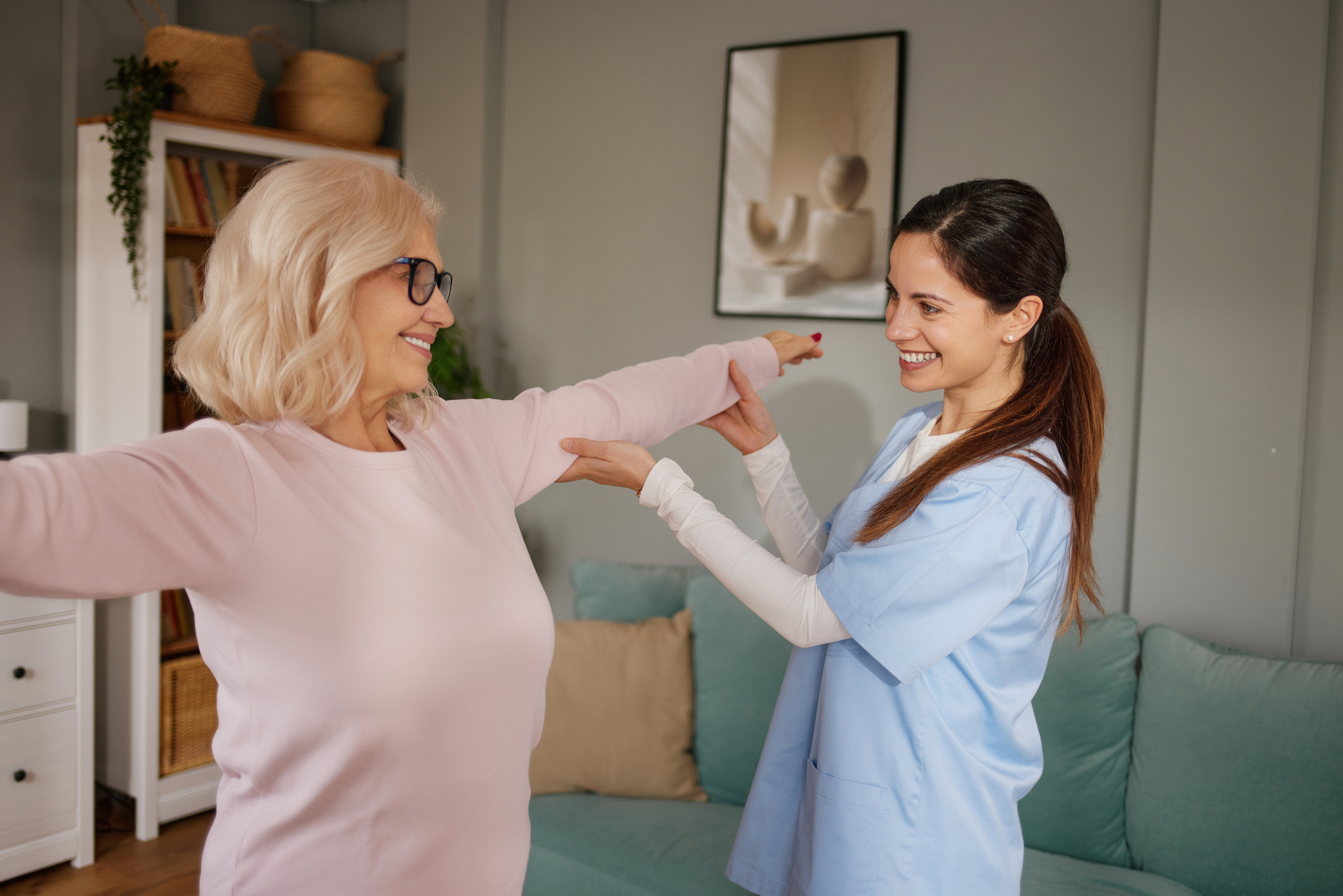 Physiotherapist helping mature adult woman with arm exercises during rehabilitation at home