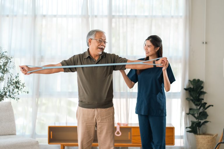 A physiotherapist assisting an older client with a mobility exercise at home