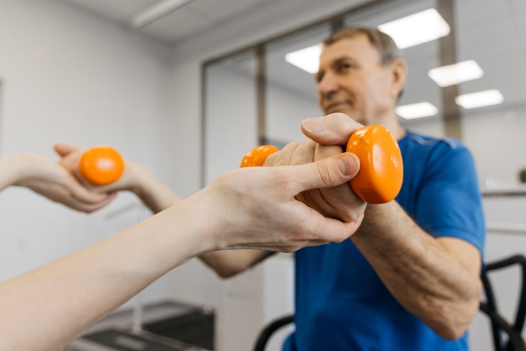 disabled man doing dumbbell exercises with NDIS physiotherapist