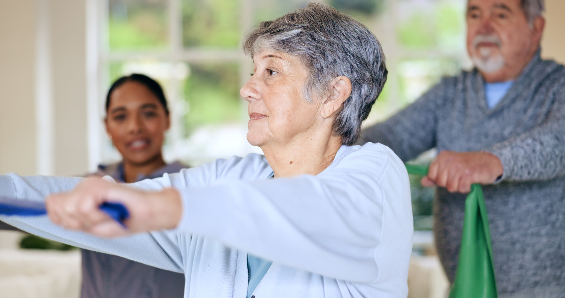 elderly client doing resistance band exercise at home with physiotherapist