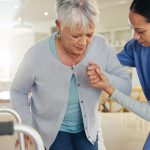physiotherapist assisting elderly client with her mobility at home