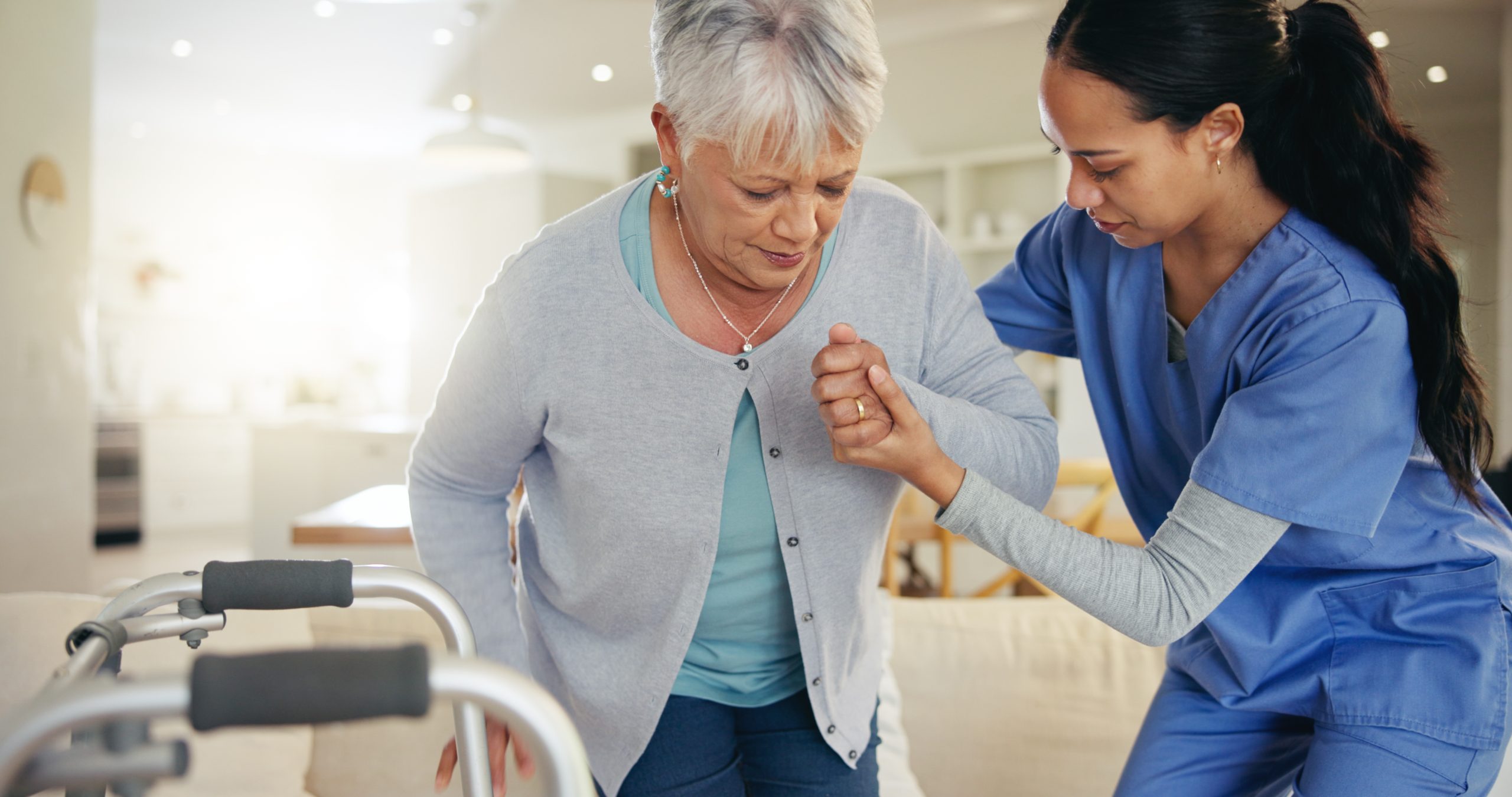 physiotherapist assisting elderly client with her mobility at home