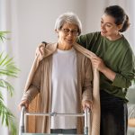 physiotherapist helping older adult with walking frame at home in Sydney