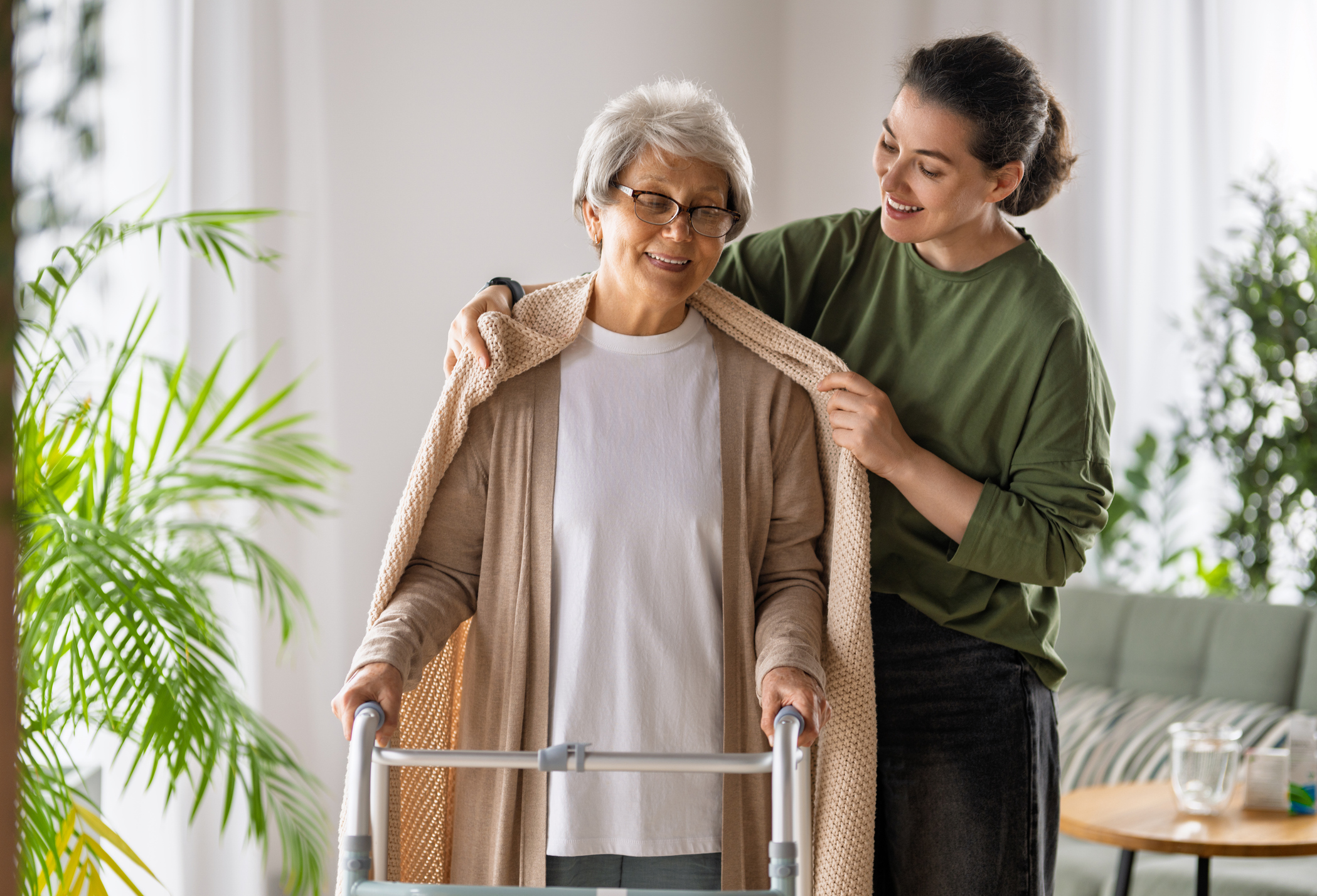 physiotherapist helping older adult with walking frame at home in Sydney