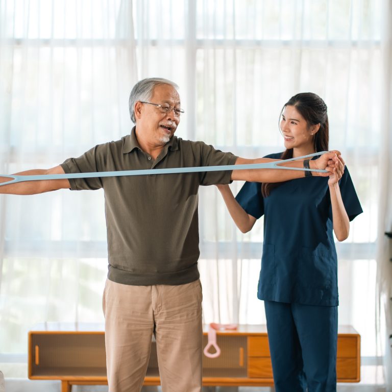 A physiotherapist assisting an older client with a mobility exercise at home