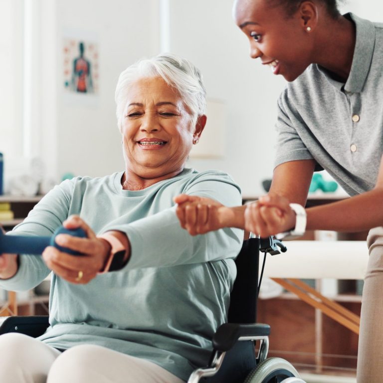 Physiotherapist helping older women with exercises in wheelchair