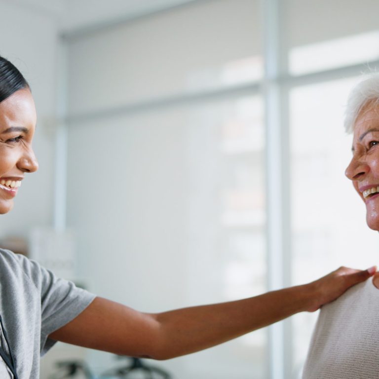 female physiotherapist smiling at elderly woman