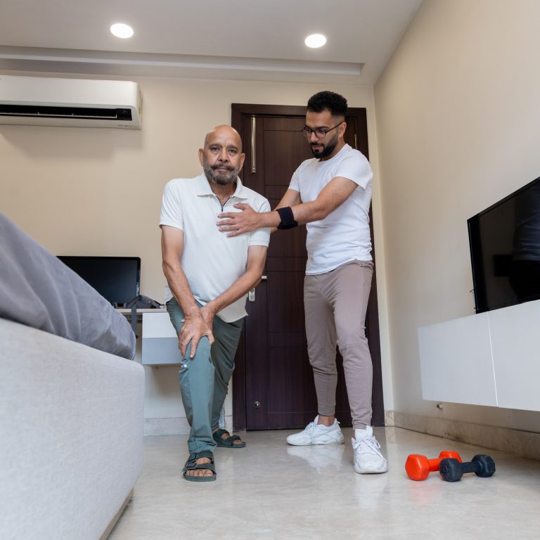 Senior Man Assisted by Caregiver During Home Physiotherapy Session