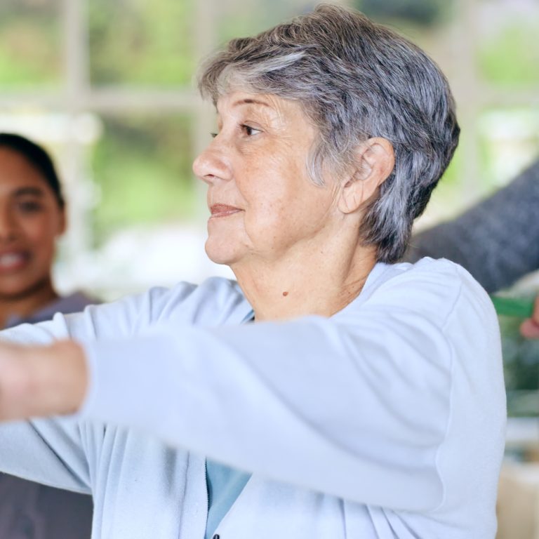 elderly client doing resistance band exercise at home with physiotherapist
