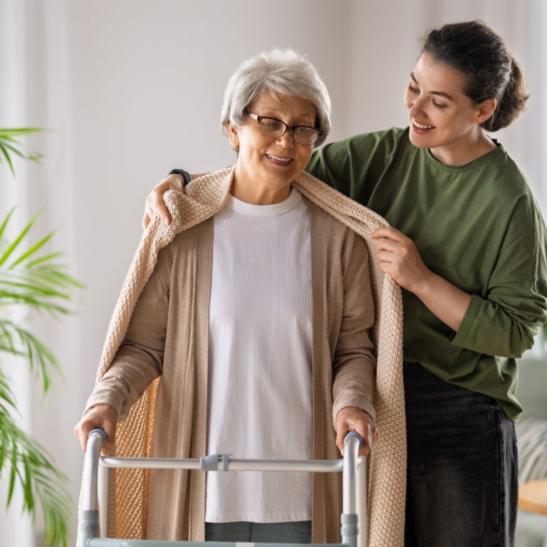physiotherapist helping older adult with walking frame at home in Sydney