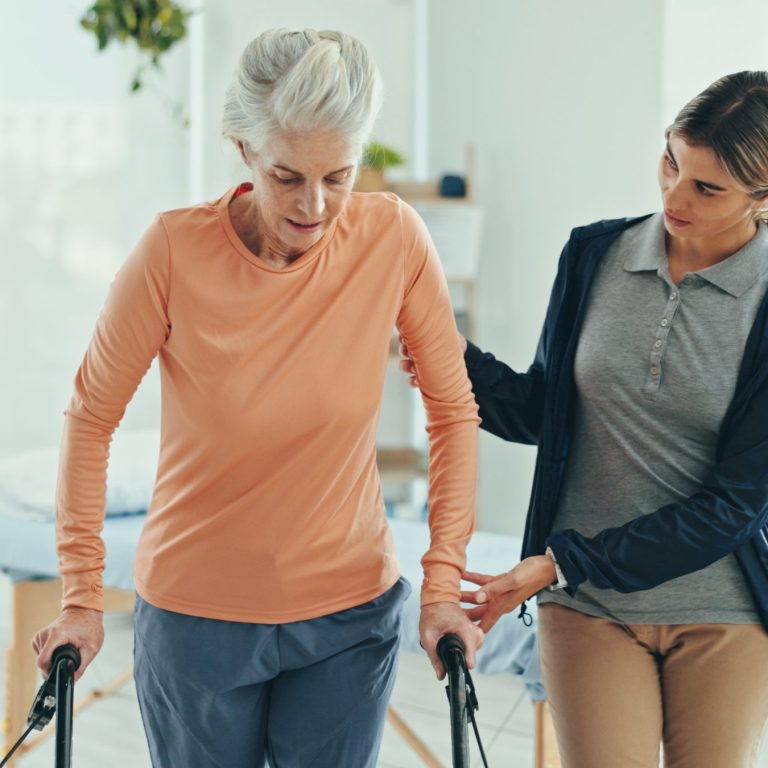 Physiotherapist helping an older client with in-home exercises as part of aged care funding